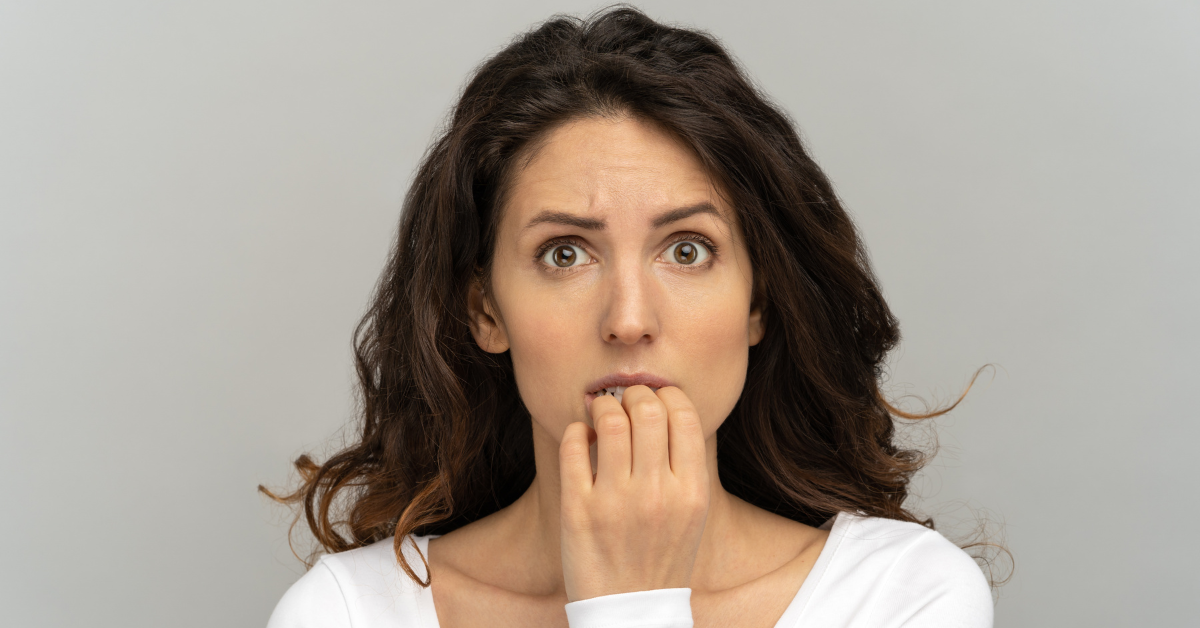 A woman bites her nails nervously.