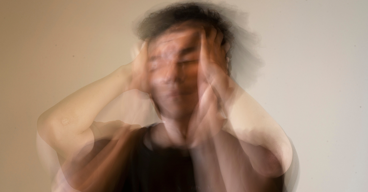 A blurred image of a man with his hands on his head.