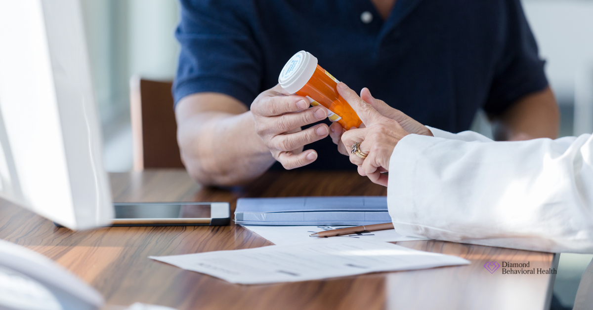 Close-up of a medical professional handing a prescription bottle to a patient across a desk, symbolizing the medical discussion and potential risks associated with Ostarine side effects.