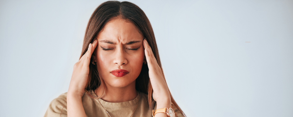 A woman holds her temples with a stressed look on her face.