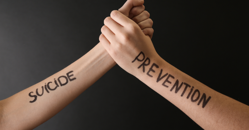 Two hands intertwined, with the words "SUICIDE" written on one arm and "PREVENTION" written on the other, symbolizing the importance of preventing suicide.