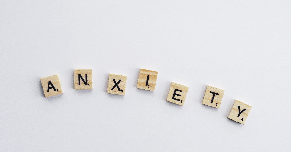 The word "ANXIETY" spelled out using wooden Scrabble tiles.