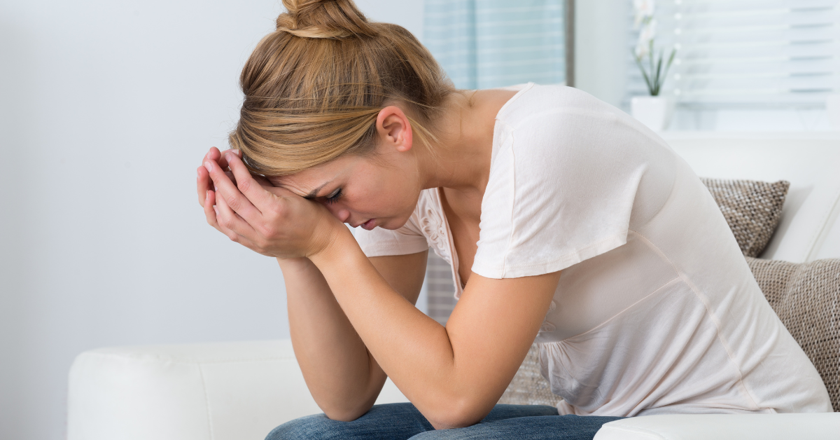 Stressed woman sitting in her bathroom with her head on her hands