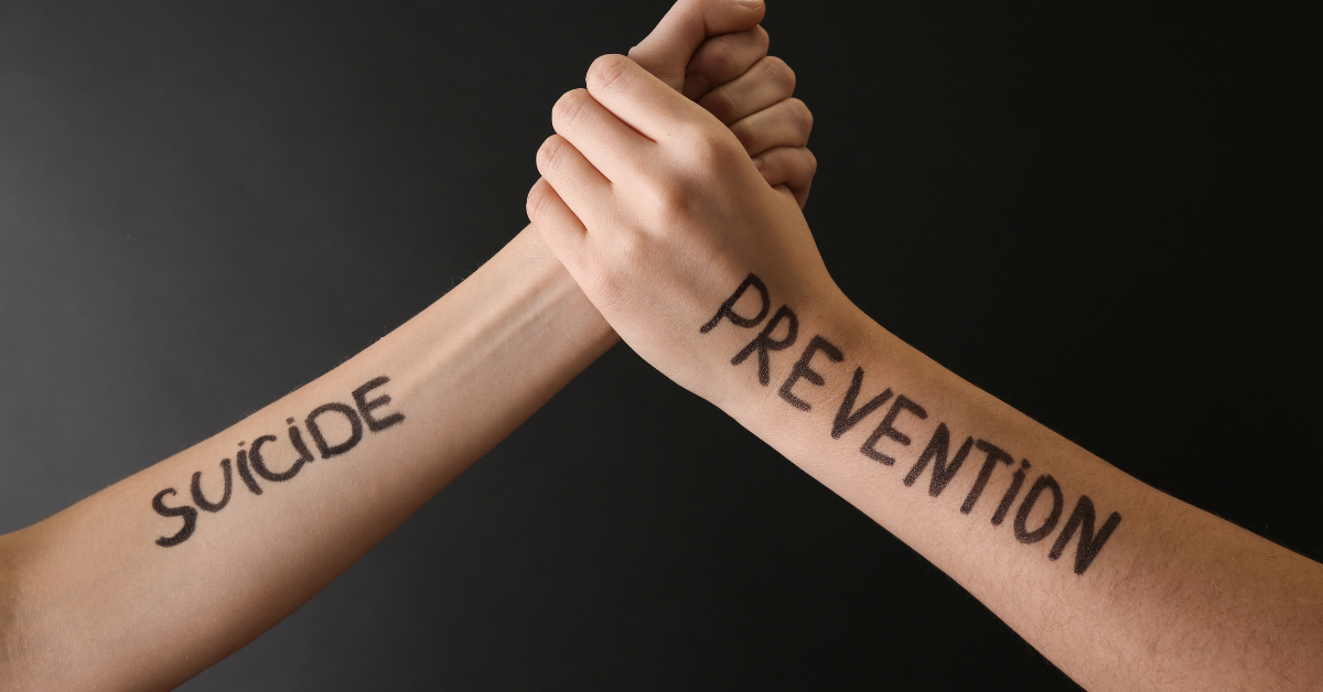 Two hands intertwined, with the words "SUICIDE" written on one arm and "PREVENTION" written on the other, symbolizing the importance of preventing suicide.