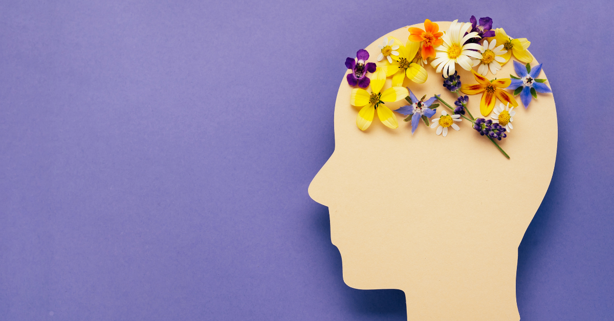 A silhouette of a head is filled with colorful flowers, symbolizing positive thoughts or mental well-being.