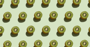 A repeating pattern of halved kiwi fruits arranged neatly against a light green background.