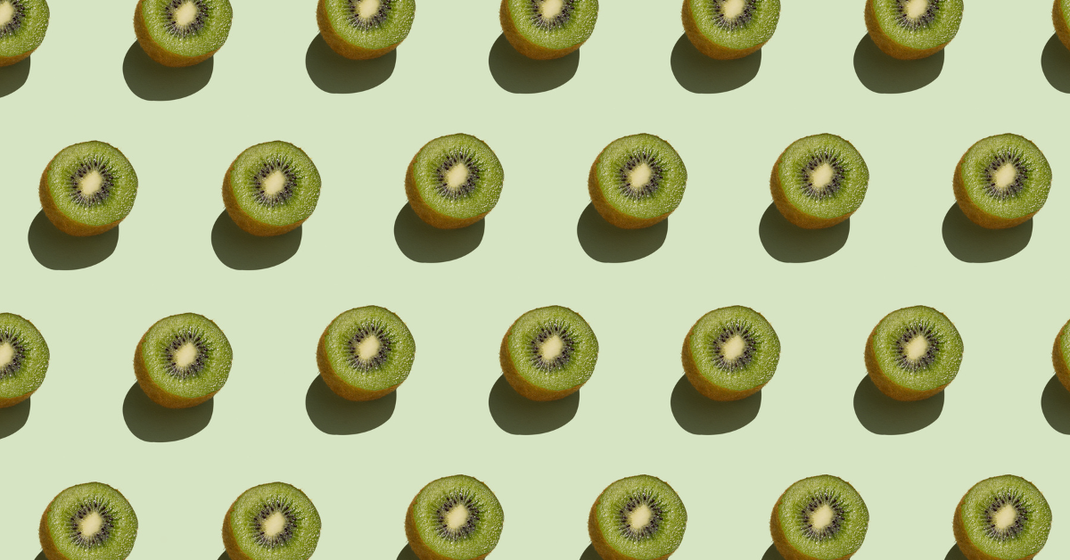 A repeating pattern of halved kiwi fruits arranged neatly against a light green background.
