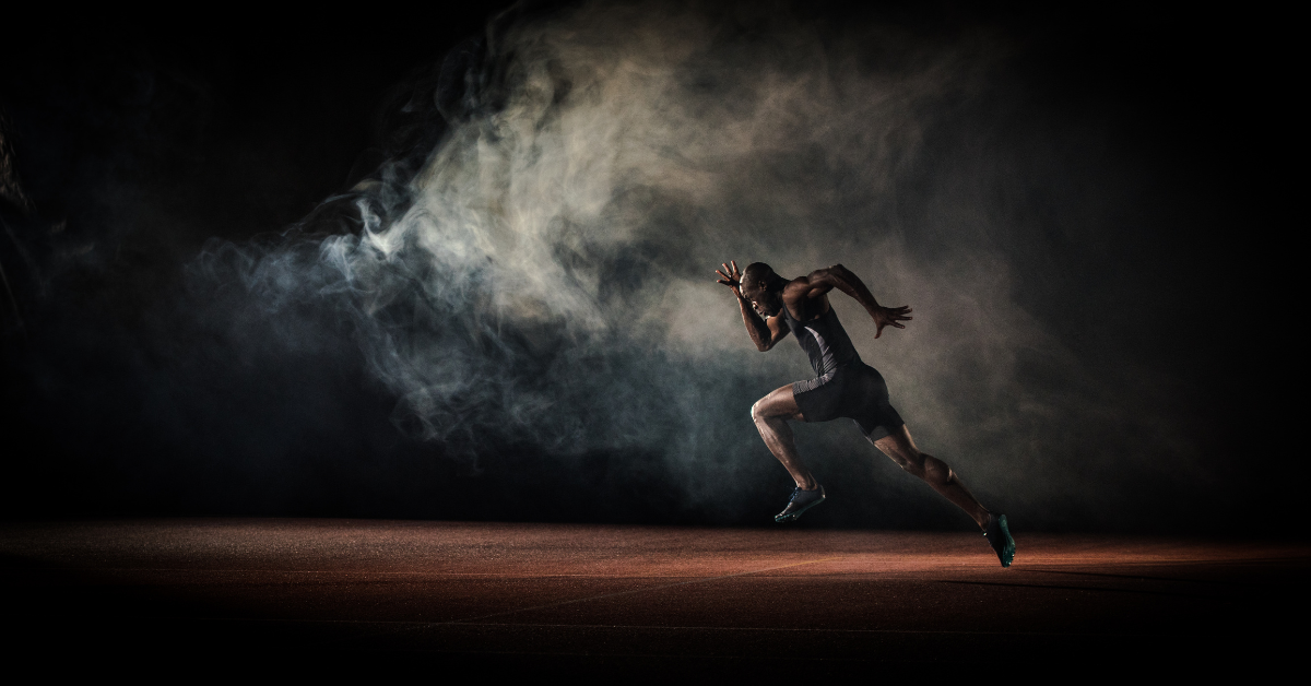 male athlete sprinting on a track with intense focus, surrounded by swirling smoke or mist in a dimly lit environment, symbolizing speed, strength, and determination.
