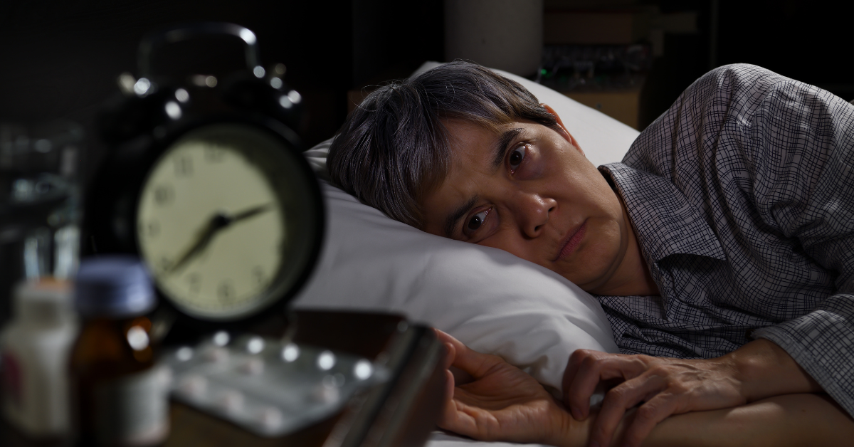 A man in bed looks at his clock.