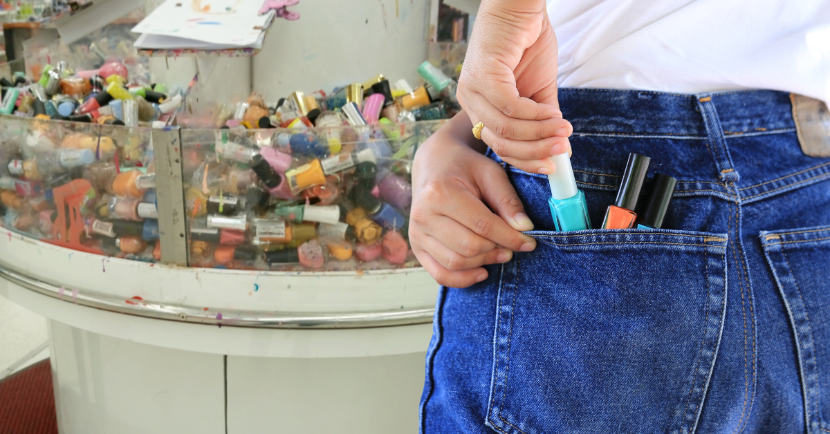 Closeup of a girl hiding nail polish bottles in her back pocket.