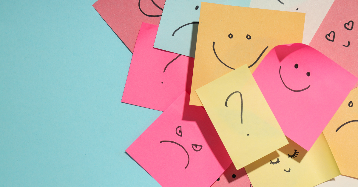 Colorful sticky notes with various hand-drawn facial expressions, including happy, sad, and confused faces, symbolizing a range of emotions and mental health awareness.