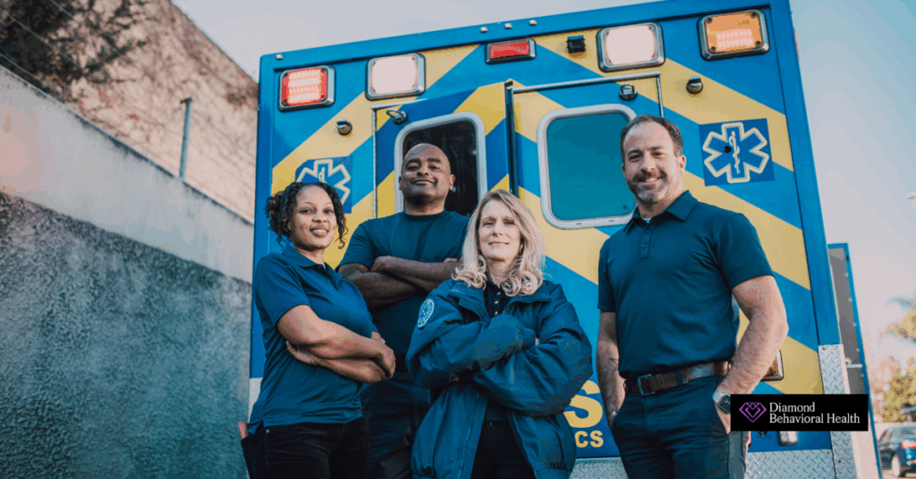 Group of confident EMS professionals standing in front of an ambulance, representing the strength of emergency medical teams and the importance of addressing mental health and burnout in EMS careers.