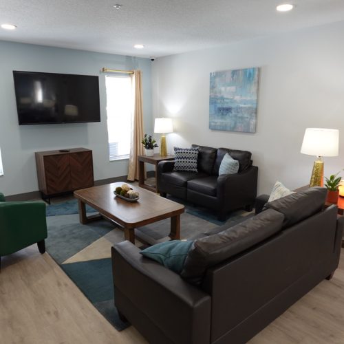 A living room with couches, a coffee table, a television, light blue and white walls.
